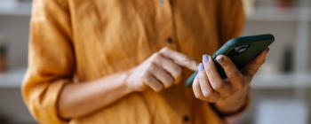 A person in a button-down shirt scrolls on a smartphone.