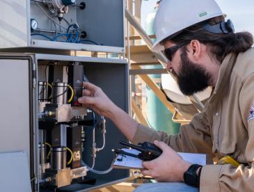 A researcher works with equipment as part of a field test of hydrogen quantification tech.