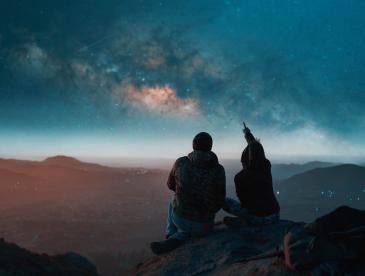 Two people on a mountaintop looking at the stars