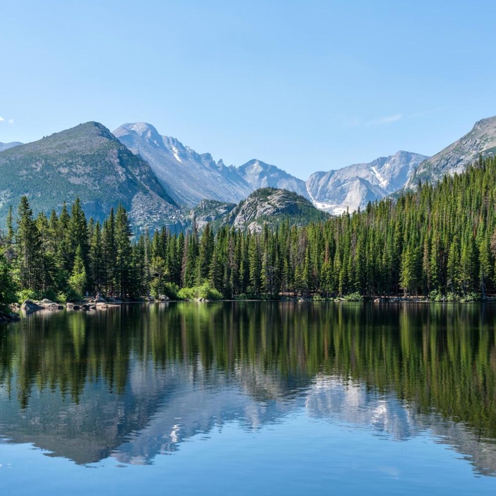 Beautiful mountains and forest by a pool of crystal clear water.